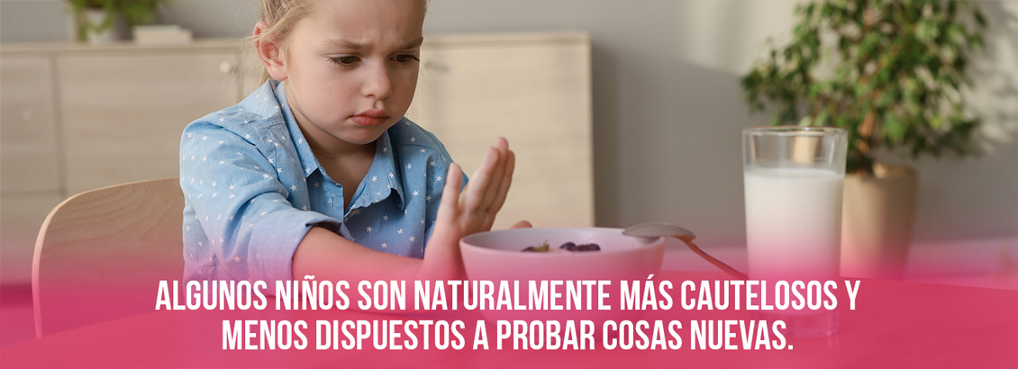 Nia con gesto triste que rechaza los alimentos sobre la mesa