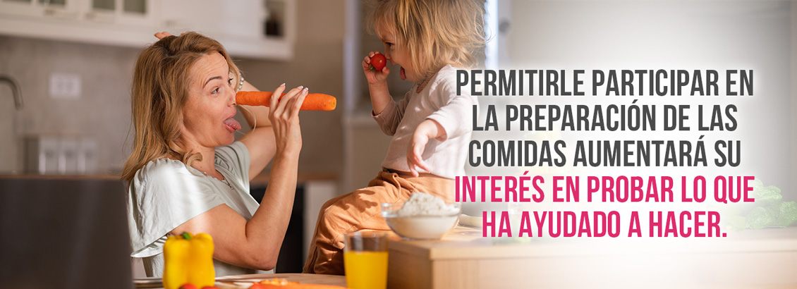 Mam e hija cocinando mientras se divierten con zanahoria y tomates